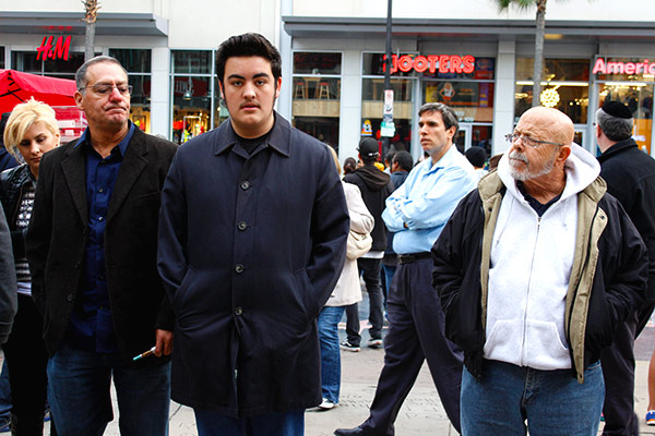 A man is in the middle of a crowd being stared down my two men on each side.